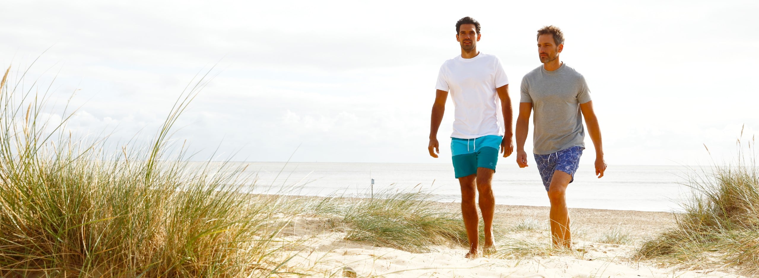 Location-based fashion photography for Joseph Turner catalogue, Two men walk up a beach dune.