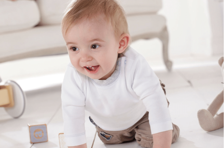 A toddler excitedly crawls across white tiles during the Silver Cross photo shoot.